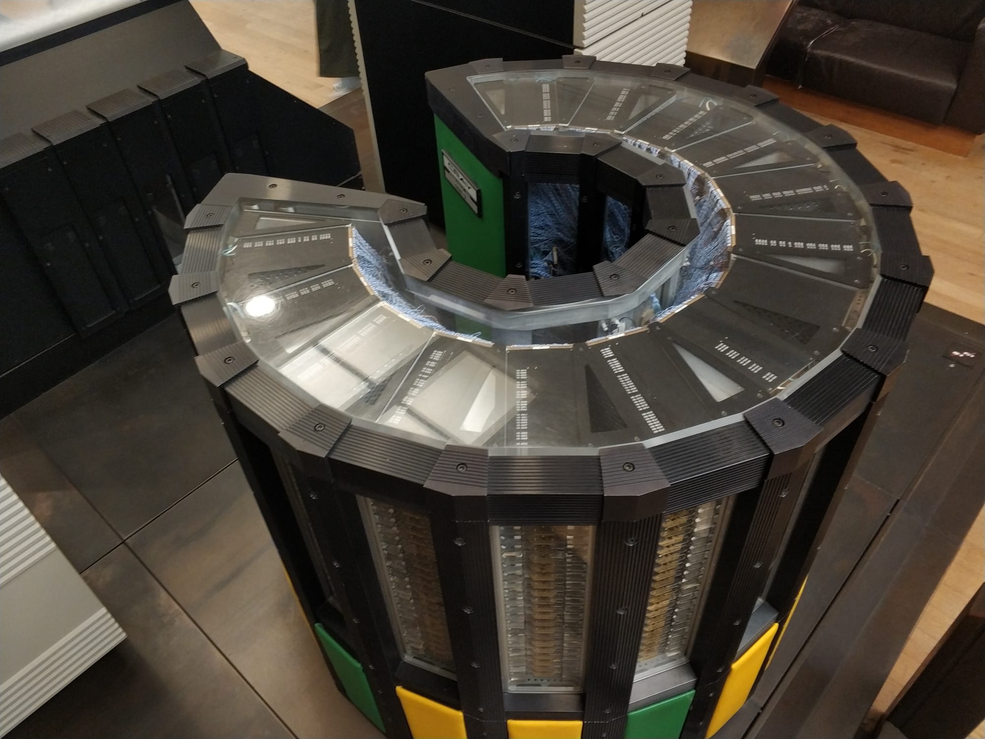 A Cray-2 computer, photographed from an angle above. It is C-shaped when looking down, about 3.5 feet tall and 2 feet across. Several pannels are transparent so you can see its insides.